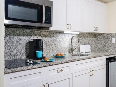 Weiße Küchenzeile mit Granitarbeitsplatte, Mikrowelle, Kaffeemaschine und kleiner Spülmaschine.