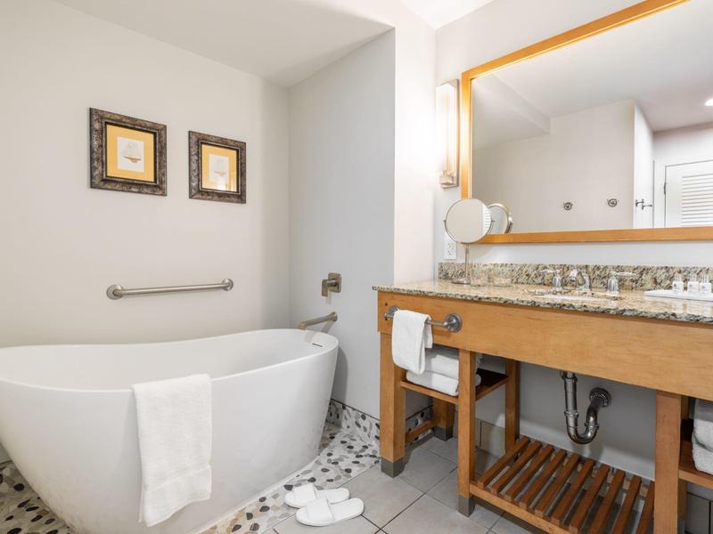 Modernes Badezimmer mit freistehender Badewanne, Holzmöbel-Waschtisch und großem Spiegel.