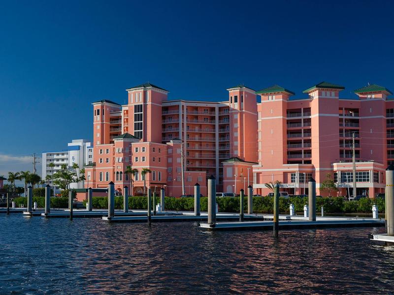 Rotes Wohngebäude am Wasser mit klar blauem Himmel und Bootsanlegern im Vordergrund.