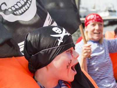 Kinder tragen Piratenkostüme mit Augenklappe und Piratentuch bei einem Fest.