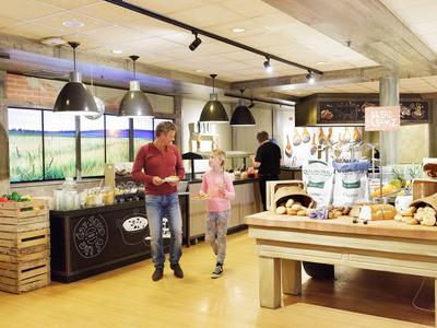 Hotel-Lobby mit Buffetbereich und Gästen, die Frühstücksbuffet erkunden.