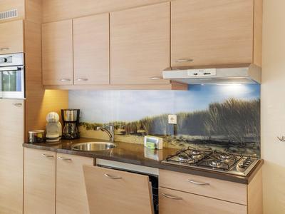 Moderne Küche mit Holzschränken, eingebautem Ofen, Gasherd und Deckenlüfter.