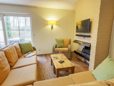 Gemütliches Wohnzimmer mit beigen Sofas, Couchtisch, Kamin und Fenster mit Blick ins Freie.