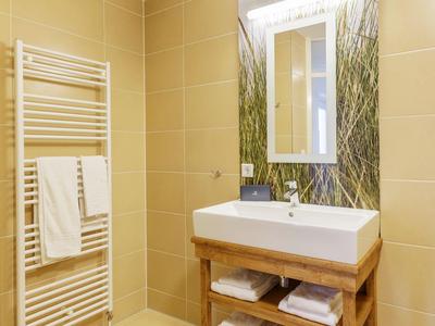 Modernes Badezimmer mit rechteckigem Waschbecken, Spiegel und Handtuchheizung an der Wand.