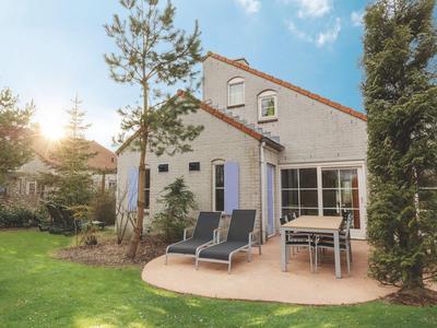 Haus mit rotem Dach, Terrasse mit Liegestühlen und Esstisch im Garten bei sonnigem Wetter