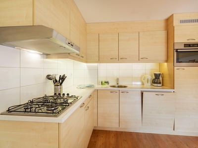 Moderne Küche mit hellen Holzschränken, Gasherd und eingebauten Geräten.