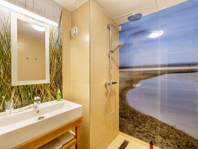 Modernes Badezimmer mit Dusche, Waschbecken, großem Spiegel und Wandbild einer Flusslandschaft.