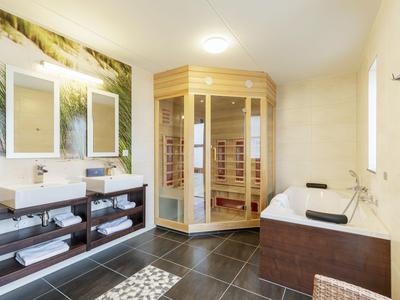 Modernes Badezimmer mit Holzsauna, Badewanne und Doppelwaschbecken.