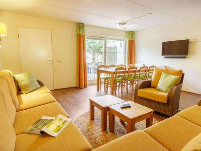 Helles Wohnzimmer mit Sitzbereich, Esstisch und Zugang zum Balkon in einer Ferienwohnung.