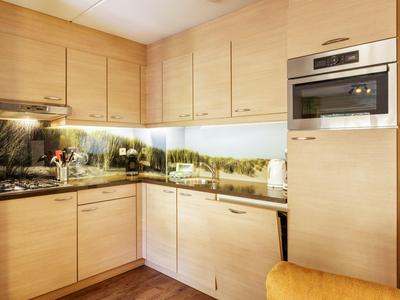 Moderne Küche mit hellen Holzschränken und Glasrückwand mit Landschaftsmotiv.