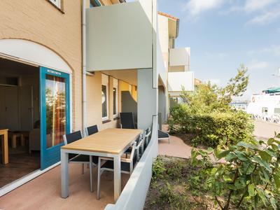 Balkon mit Tisch und Stühlen an einem Hotelzimmer mit Blick auf Grünflächen.