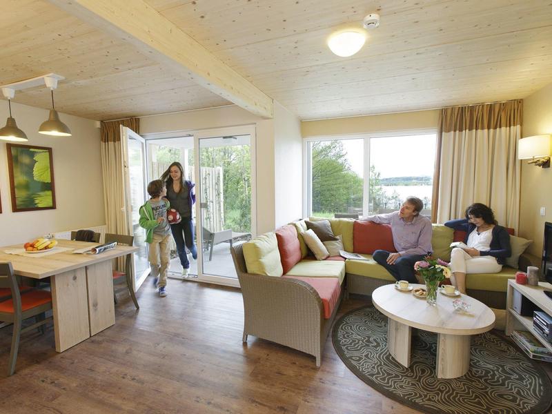 Sala acogedora con sofá, alfombra, mesa de centro y dos personas en una casa de vacaciones.