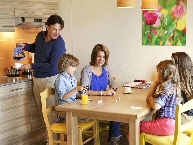 Familia desayunando en una mesa de madera en una cocina moderna con ambiente alegre.