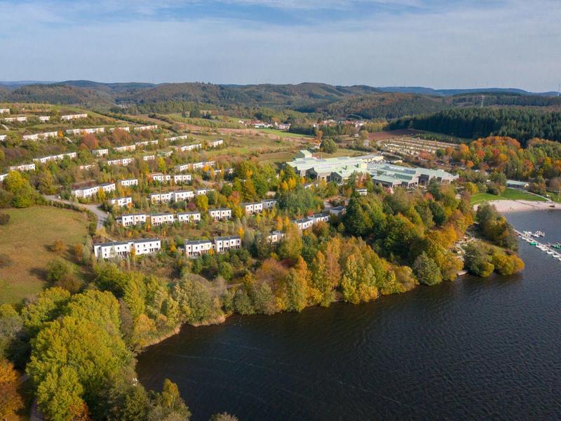 Vista aérea de un parque vacacional con muchos edificios cerca de un lago y un entorno boscoso.