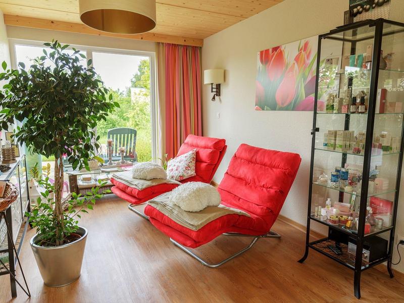 Acogedora sala con sillones rojos, plantas y vitrina de vidrio con objetos decorativos.