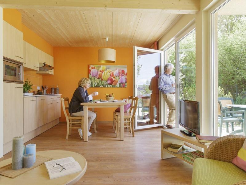 Acogedor salón con mesa, sillas y puerta abierta a terraza y jardín.