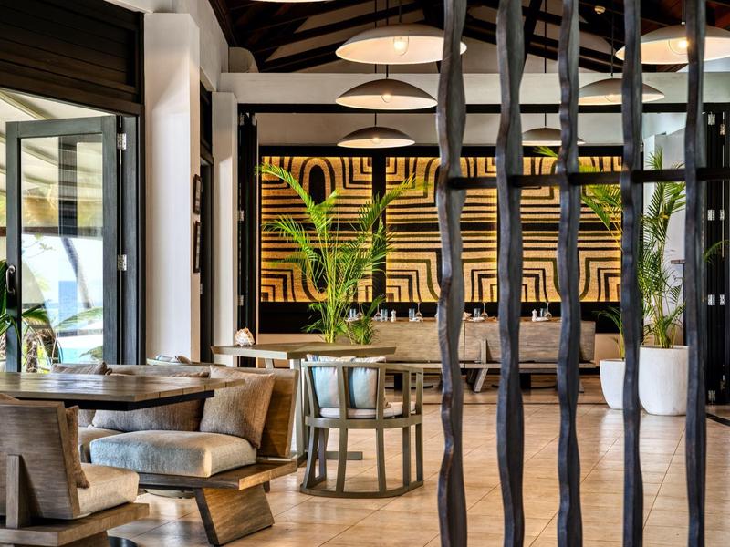 Ristorante hotel moderno con sedie in legno, tavoli e decorazioni murali eleganti.