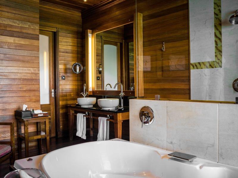 Bagno moderno con pareti in legno, vasca da bagno autonoma e specchio illuminato.