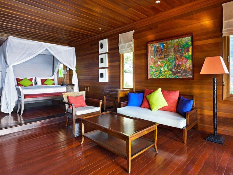 Camera d'hotel elegante con letto a baldacchino, area divano e dettagli in legno.