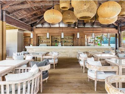 Rustikale Hotelbar mit Holzinterieur und gemütlichen Sitzgelegenheiten unter Lampen aus Rattan.
