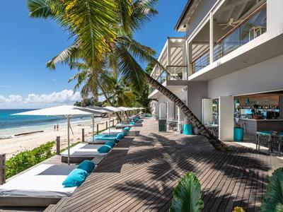 Hôtel de plage avec palmiers, chaises longues et vue sur la mer sous un ciel dégagé