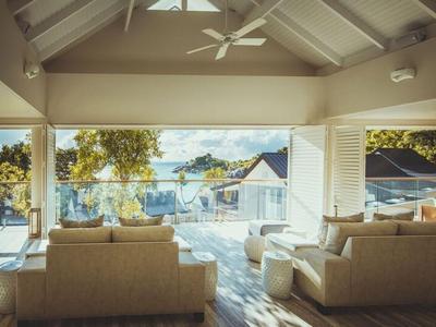 Salon lumineux avec grande fenêtre donnant sur une terrasse ensoleillée et un jardin