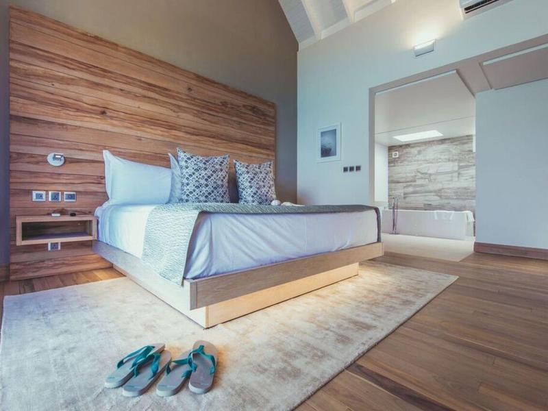 Moderní ložnice s velkou postelí, dřevěnou stěnou a útulným kobercem.