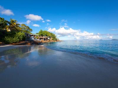 Spiaggia con acqua limpida e palme sotto un cielo azzurro in una giornata di sole