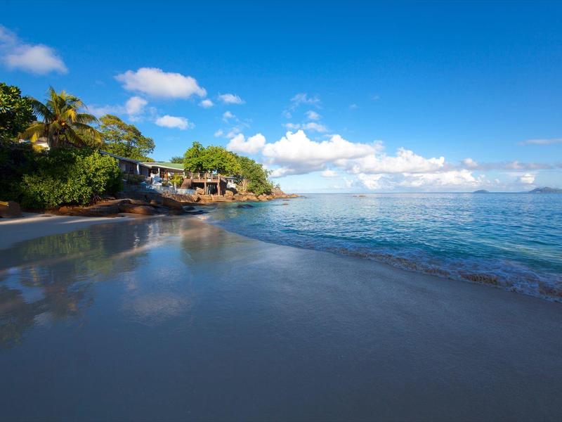 Spiaggia con acqua limpida e palme sotto un cielo azzurro in una giornata di sole