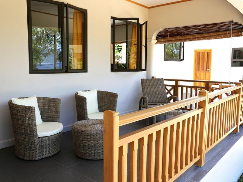 Accogliente balcone con poltrone in vimini e ringhiera in legno in una camera d'hotel.