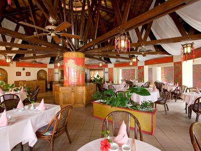 Interiér restaurace s dřevěnými trámy a dekorovanými stoly, stylově zařízený.