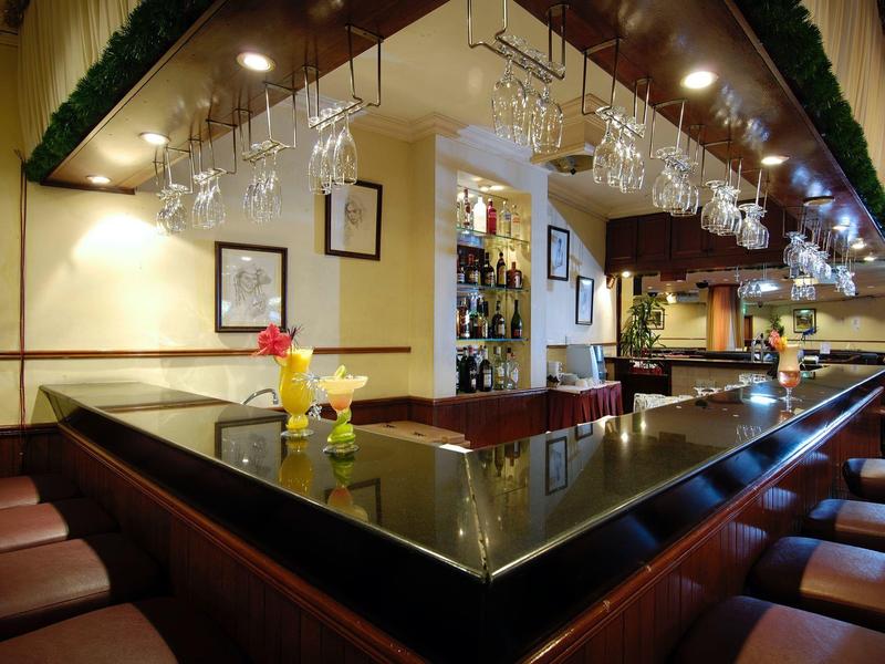 Gezellige hotelbar met donker houten bar, hangende glazen en comfortabele zitplaatsen.