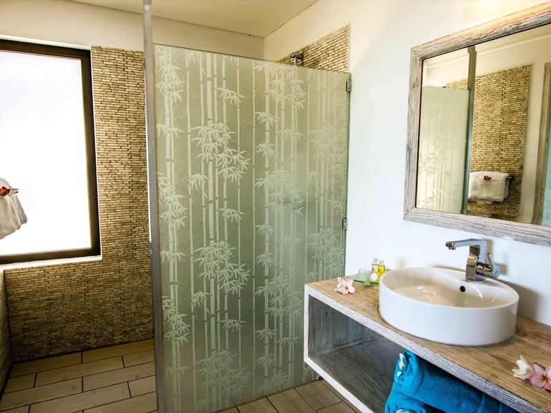 Bagno luminoso con doccia in vetro, grande specchio e lavabo rotondo.