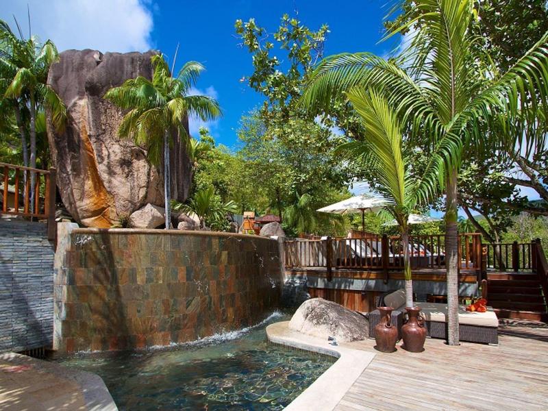 Piscina con cascata e area relax circondate da palme in hotel tropicale