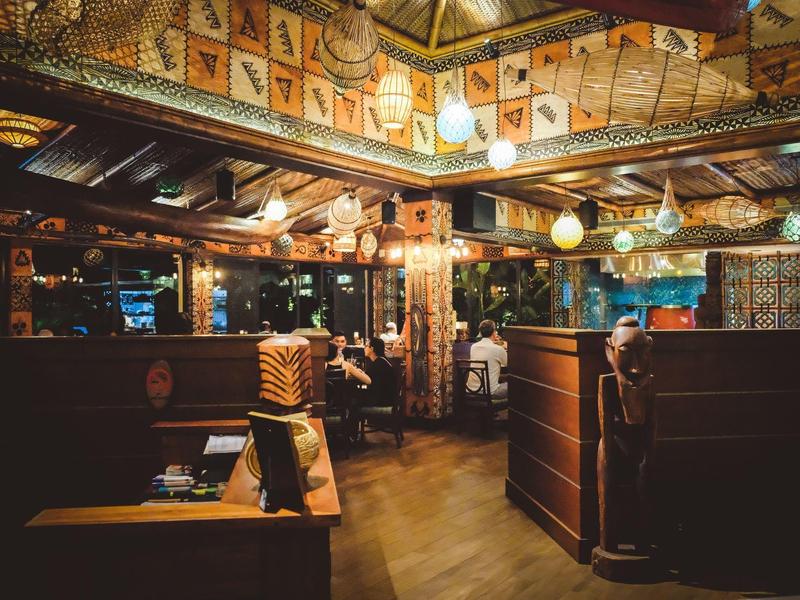 Gemütliche Holzinnenraum-Bar mit nautischen Dekorationen und bunten Wimpeln an der Decke.