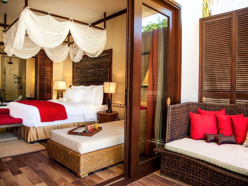 Gemütliches Schlafzimmer mit Baldachinbett, Holzmöbeln und roter Dekoration.