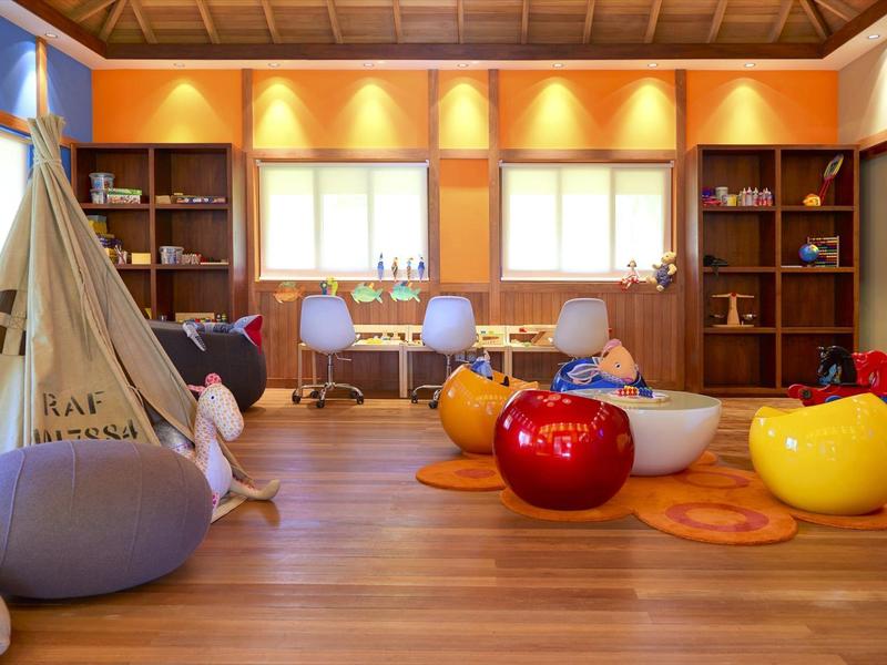 Bunter Kinderspielraum mit Zelt, Stühlen, Apfelkissen und großem Fensterlicht.