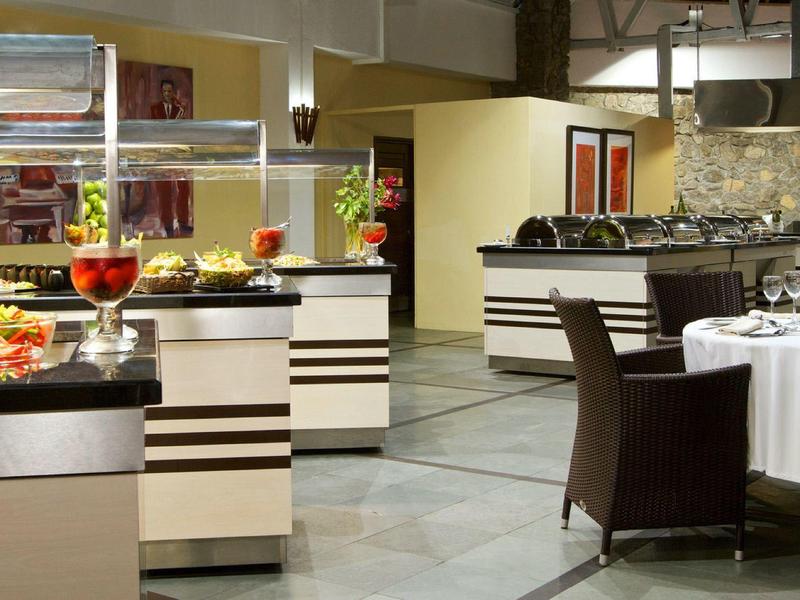 Modernes Restaurant mit Buffet und eingedeckten Tischen, warmes Licht, helle Wände und schwarze Möbel.