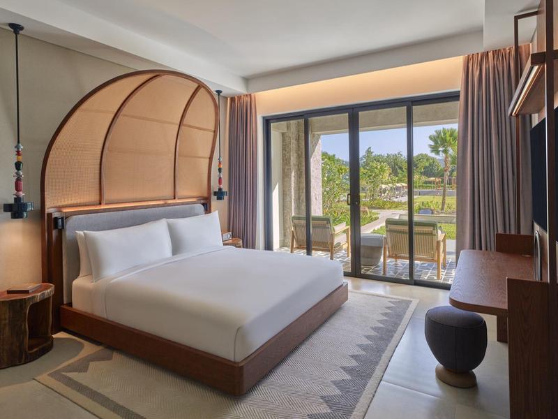 Modernes Schlafzimmer mit großem Bett, abgerundetem Kopfteil, Balkon und viel natürlichem Licht.