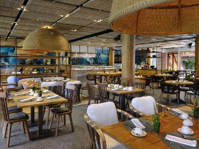 Moderní hotelová restaurace s prostřenými stoly a ratanovými lampami.