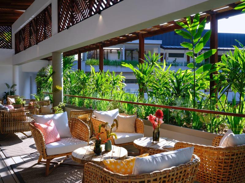 Pohodlná posezení s ratanovým nábytkem na verandě s výhledem na zeleň.