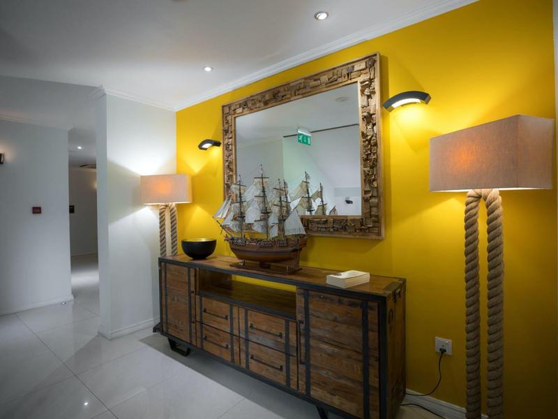 Hallway with yellow wall, wooden cabinet, large antique mirror, and decorative sailing ship model.