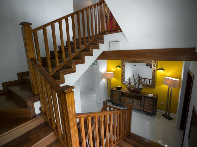 Wooden staircase with railings and dresser with decor in a brightly lit hallway.