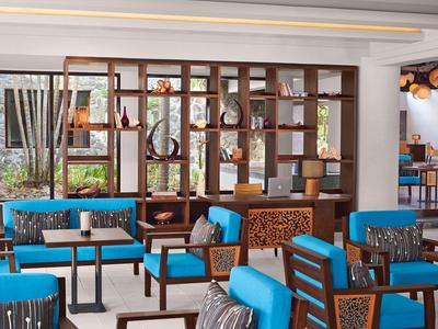 Modern hotel lounge area with blue chairs and wooden shelf wall divider.