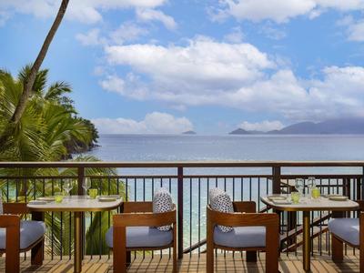 Terrasse mit Holztisch und Stühlen mit Blick auf das Meer und bewölkten Himmel
