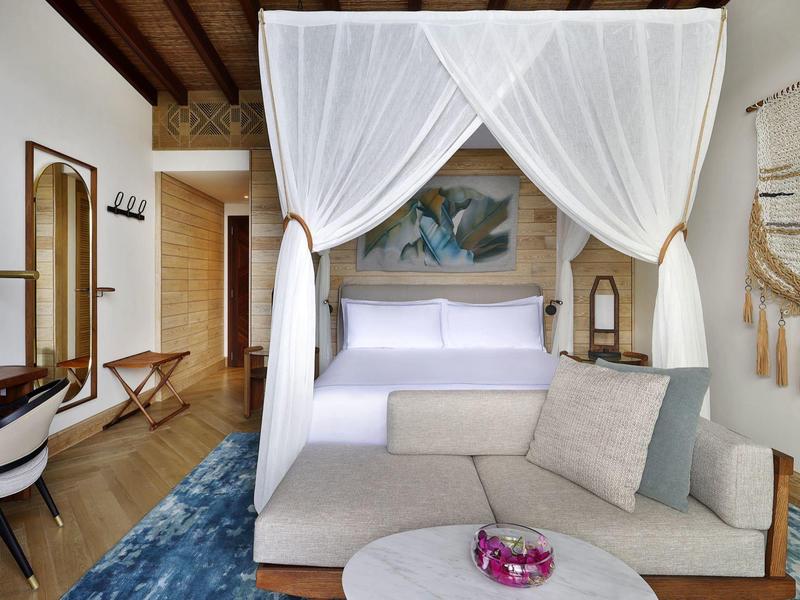 Schlafzimmer mit Himmelbett, Sofa, Tisch und einer blauen Teppichmatte in modernem Stil.