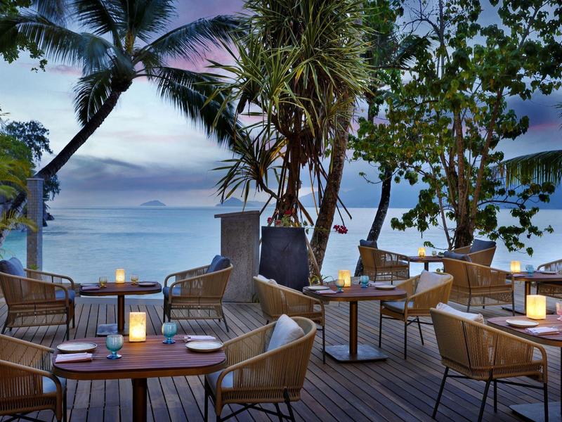 Gemütliche Außenrestaurant-Terrasse mit Kerzen und Meerblick bei Sonnenuntergang