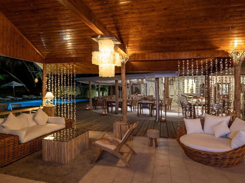 Cozy outdoor area with wooden ceiling, armchairs, and sofas in a hotel lounge.