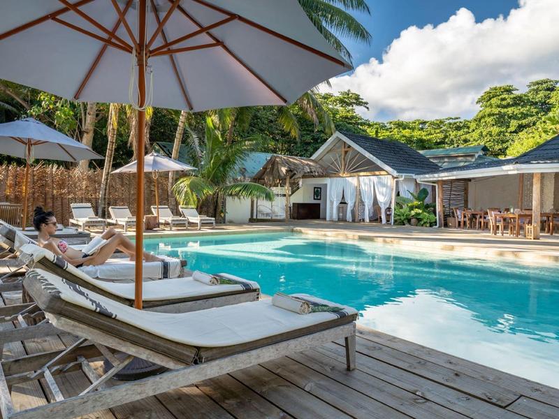 Inviting hotel pool with sun loungers and umbrellas surrounded by tropical greenery.
