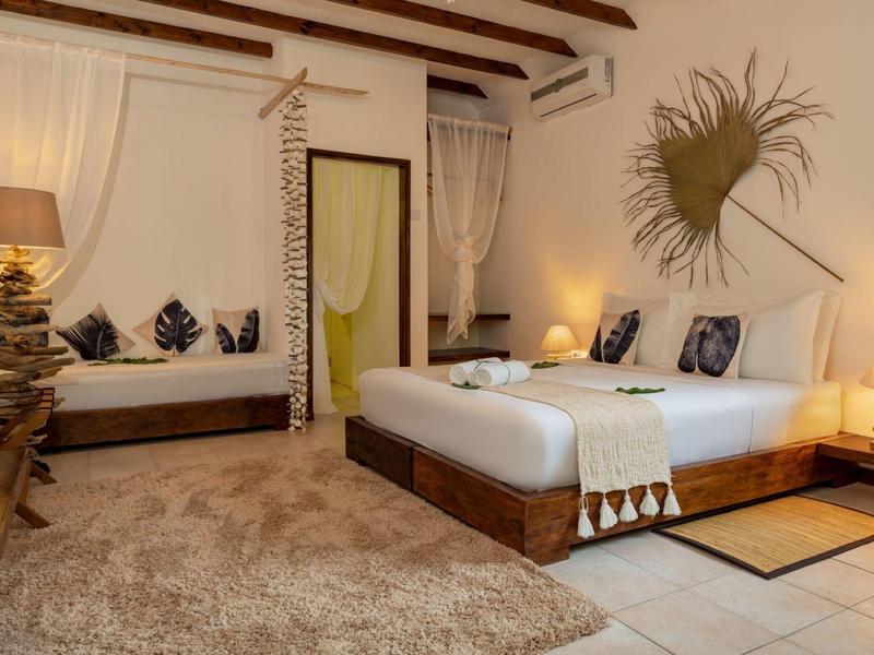 Cozy hotel room with large bed, sofa, rug, and decorative wall hanging.